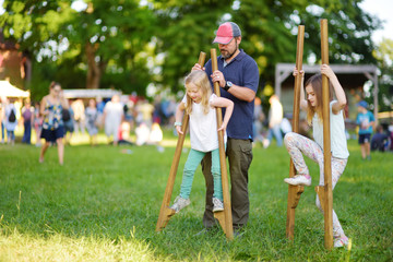 Father and children walking on stilts during annual Medieval Festival, held in Trakai Peninsular Castle.