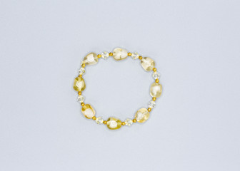 pale yellow colored and variously sized beads bracelet on gray background