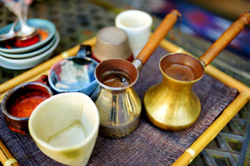 Coffee brewed in a copper cezve on a cute tray in cozy kitchen. Colourful ceramic cups and fresh hot coffee.
