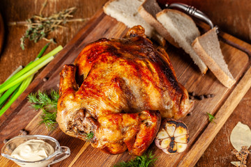 Festive home baked chicken grill for the whole family. chicken lies on a wooden board with sauce and vegetables.