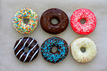 Donuts of different colors on cardboard, top view