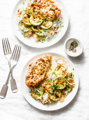 Served lunch - dijon baked chicken with rice, courgettes and fried onions on light background, top view