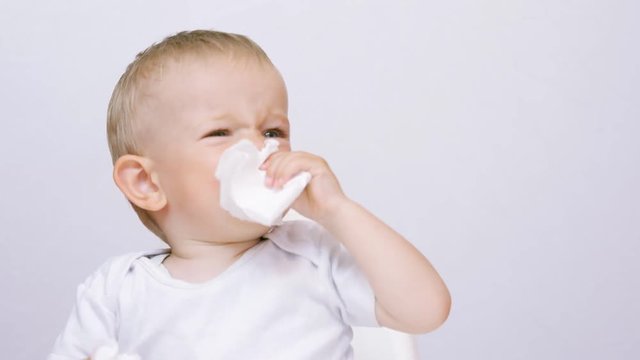 Amusing baby blowing nose, mother hand giving napkins, flue hygiene 