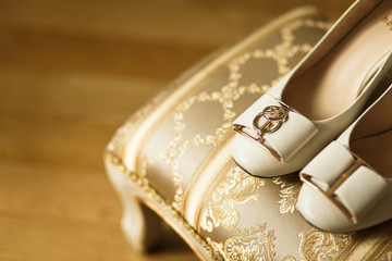  Wedding rings and shoes of the bride on the ottoman for the legs. Beautiful background for a wedding article