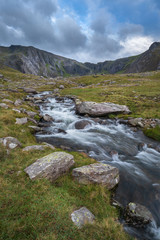 Moody landscape image of river flowing down mountain range near Llyn Ogwen and Llyn Idwal in Snowdonia in Autumn