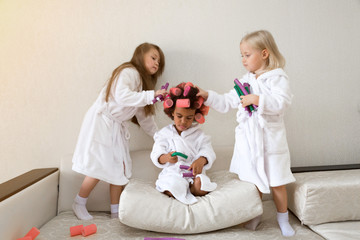 Black girl wind curlers in her hair. Little girls play with hair curlers and hairpins.