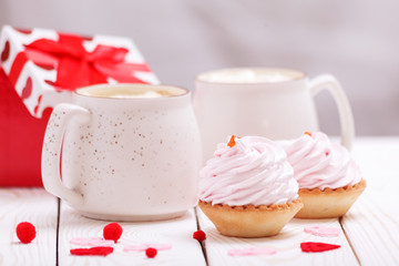 Obraz na płótnie Canvas Two cups of coffee and cupcakes with pink cream for Valentine's Day or Birthday, wedding day. White wooden background. Selective focus