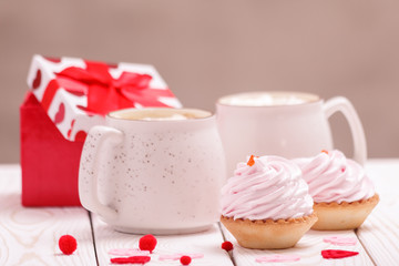 Two cups of coffee and cupcakes with pink cream for Valentine's Day or Birthday, wedding day. White wooden background. Selective focus