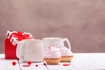 Two cups of coffee and cupcakes with pink cream for Valentine's Day or Birthday, wedding day. White wooden background. Selective focus