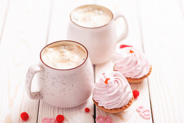 Two cups of coffee and cupcakes with pink cream for Valentine's Day or Birthday, wedding day. White wooden background. Selective focus