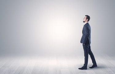 Obraz premium Successful businessman walking in front of an empty wall with briefcase on his hand 