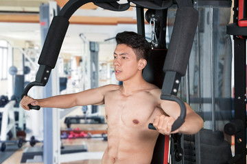 Fototapeta premium Muscular man exercising with fitness machine