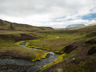 Fototapeta na wymiar A beautiful river with a green moss and hills in clouds. Iceland, perfect destination for hikers. The Legendary Laugavegur Trek.