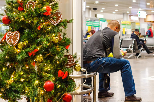 The Man Waits For Flight At The Airport In New Year. New Year And Christmas At The Airport