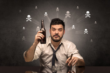 Loser drunk man sitting at table with skulls concept around
