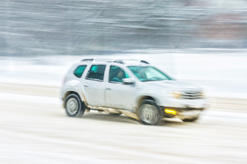 Fototapeta na wymiar Driving in snow. Motion in blur car in heavy snowfall in city road. Abstract blur winter weather background