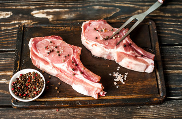 Raw pork on wooden table with salt and pepper