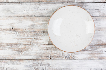 empty white dishes (plate, bowl) on a white wooden background (table), top view, copy space, mock-up
