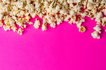 Scattered cooked popcorn on pink background with copy space. Сoncept of leisure