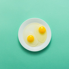 Egg crack and yolk in plate on green background, top view, flat lay