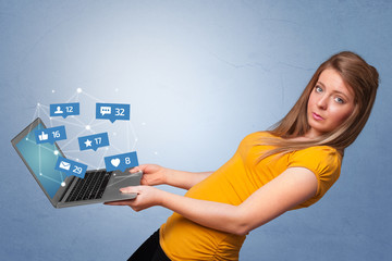 Woman holding laptop with different types of social media symbols and icons
