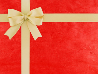 brown beige ribbon bow wrapped cross on bright red paper with abstract striped pattern, double tied bow and vivid red cardboard for cover gift box decor or greeting card, flat lay close up top view