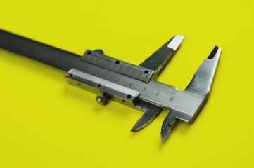 Vernier caliper of gray color on yellow table