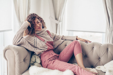 Teenage girl in sweater and jumpsuit on a couch