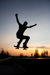 Silhouette of man on skateboard during the jump