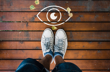 man with a shoes standing next to eye icon on wooden floor