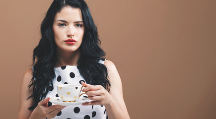 Young woman drinking coffee on a solid background