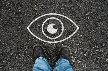  man with a shoes standing next to eye icon on asphalt