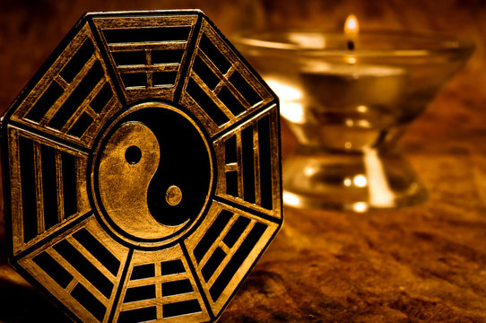 yin yang with i-ching symbols with candle in background