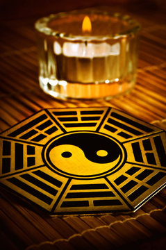 yin yang with i-ching symbols with candle in background