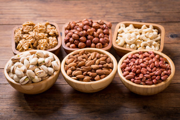 various bowls of nuts on wooden table
