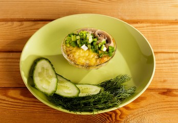 A portion of julienne with cucumbers and dill on a wooden table.