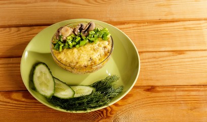 A portion of julienne with cucumbers and dill on a wooden table.