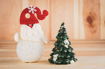 Toy snowman in a red hat is luminous shot large on a wooden background