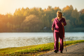 Active senior woman hiking walks at colorful Sunny autumn park