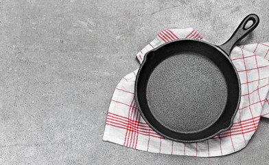 Cast iron pan on a grunge concrete background with copy space. Empty iron pan, top view or high...