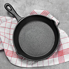Cast iron pan on a grunge concrete background with copy space. Empty iron pan, top view or high angle shot.