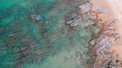 Fototapeta na wymiar Aerial drone top view of beautiful sandy beach and sea ocean water with rocks during sunny summer day