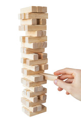 Man's hand taking or putting a block to an unstable and incomplete tower of wooden blocks. Concept...