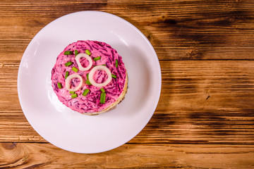 White plate with russian traditional new year salad herring under fur coat on wooden table. Top view