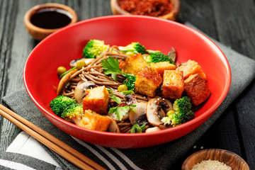 Soba noodles with vegetables and fried tofu in a bowl. 