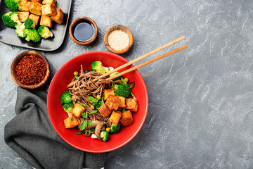 Soba noodles with vegetables and fried tofu in a bowl. Top view. 