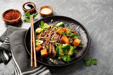 Soba noodles with vegetables and fried tofu in a bowl. 