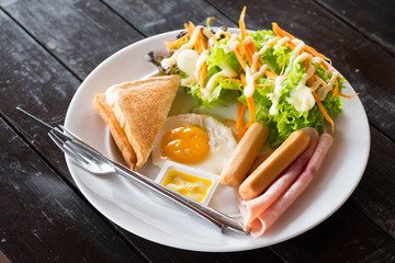 The American Breakfast set ,toast bread ,butter, fried egg ,sausage,  hams and salad.