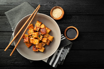 Fried tofu with sesame seeds and spices on black background. - obrazy, fototapety, plakaty