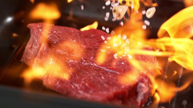 Super slowmotion footage of throwing fresh beef meat and seasoning on ignited pan, 1000fps 4k